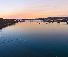 Sun setting over Wray Street Oyster Shed, Batemans Bay. Image courtesy of Destination NSW.